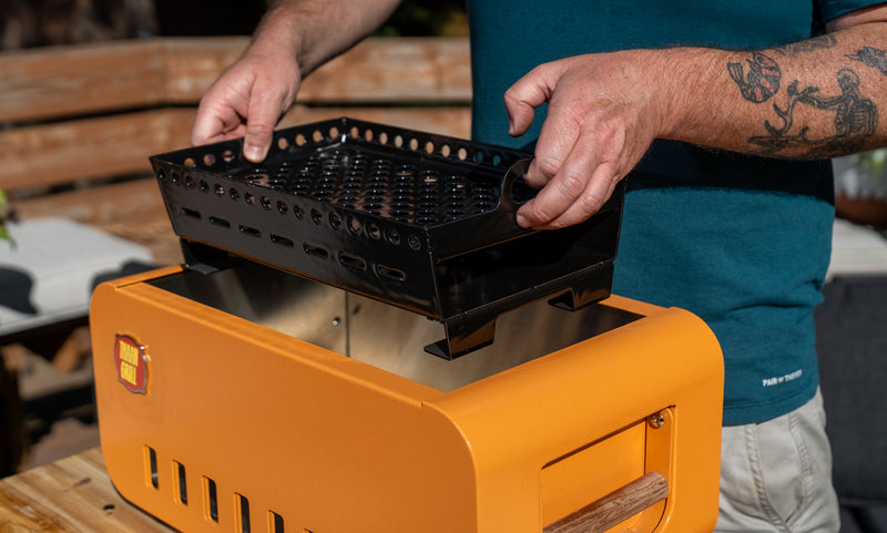 Ash box pulled from the Thaan Grill being emptied into a metal bucket