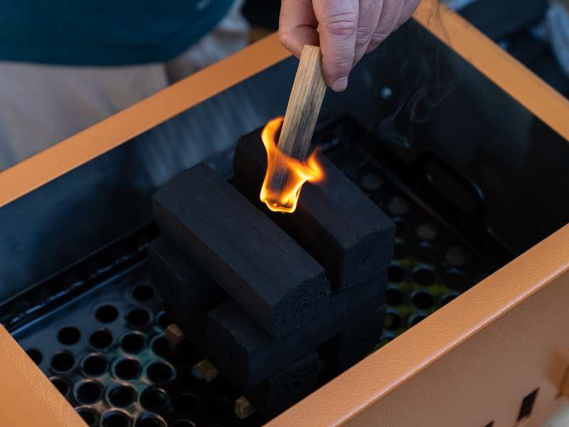 Fatwood firestarter sticks tucked into a mound of Thai-style lump charcoal in a Thaan Grill