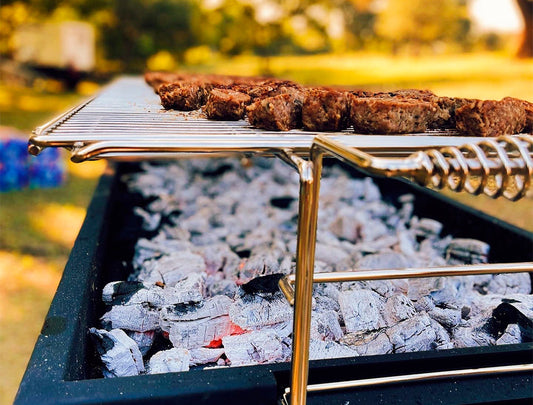 Charcoal coals glowing red with ashy white edges, banked to one side of the Thaan Grill