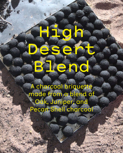 High Desert Blend charcoal briquettes in a metal tray on desert ground. A charcoal briquette made from a blend of oak, juniper and pecan shell charcoal.