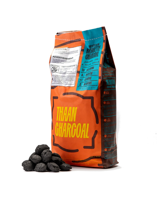 Bag of Thaan High Desert Blend briquette charcoal, 9 lb, with a pile of pillow-shaped briquettes