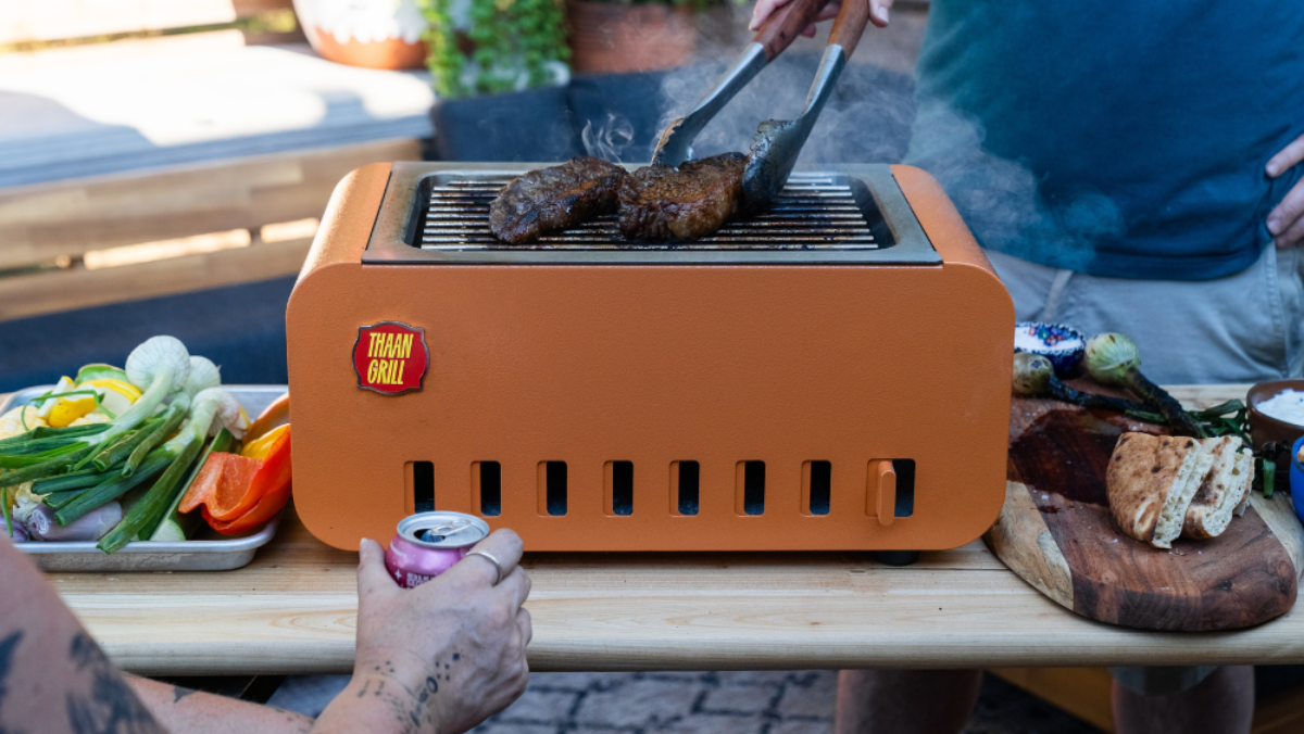 Portable grill with food being cooked on a table outdoors
